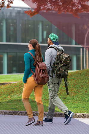 Two students walk across a campus in autumn